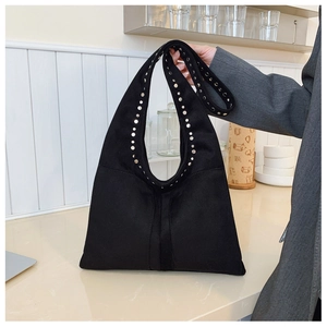 Détail du cabas en daim noir avec rivets métalliques et large bandoulière
