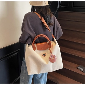 Detail view of large canvas tote bag with leather handles and metallic triangle logo