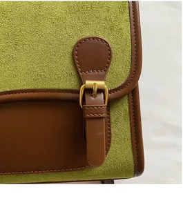 Detail of vintage metal buckle on olive green suede and brown leather flap bag