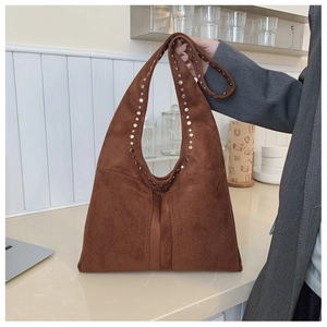 Détail d'un sac bandoulière vintage en daim marron orné de rivets métalliques argentés
