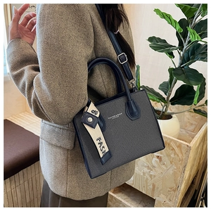 Détail d'un petit sac carré bleu marine avec texture diagonale et foulard en soie décoratif