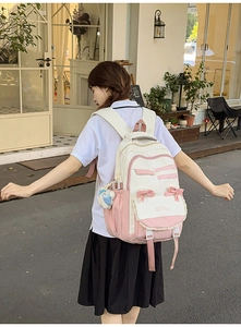 Detailed view of pink and white school backpack with lace, bow, and bear pendant
