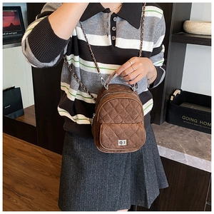 Detail of brown quilted suede mini backpack with gold chain strap and turn-lock pocket