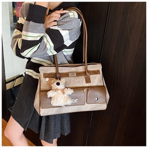Detail view of large tote bag with marble pattern, leather trim and bear charm accessory