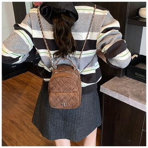 Rear view of a model wearing the brown quilted mini backpack with leather-chain straps