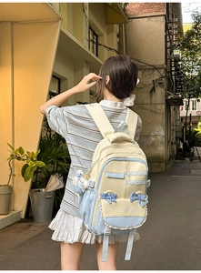 Detail of yellow and blue patchwork backpack with lace trim and bow on a model