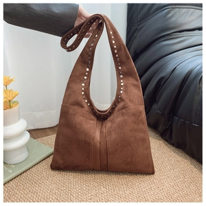 Détail du sac cabas en daim marron avec rivets métalliques et texture de style vintage