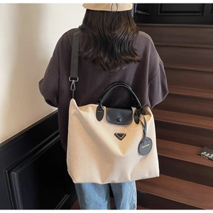 Detail of canvas tote bag with black leather handles and detachable wide shoulder strap