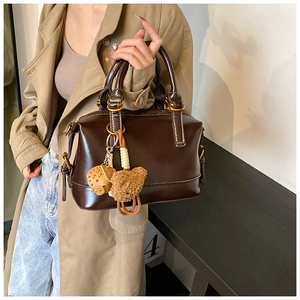 Detail of dark brown vintage Boston bag with plush bear charm and glossy finish