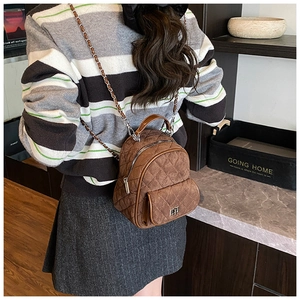 Close-up of brown quilted mini backpack with metal chain strap and luxury texture
