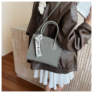 Détail du sac cabas vintage vert sauge avec anses et breloque en tissu de la marque