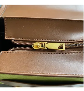 Detail of smooth gold zipper on brown leather backpack with green suede lining
