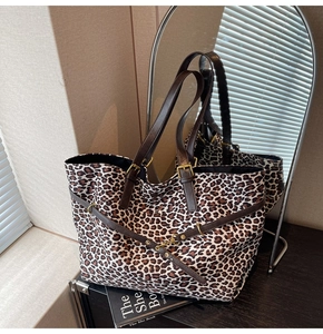 Detail of leopard print tote bag with brown leather handles and gold metal buckles