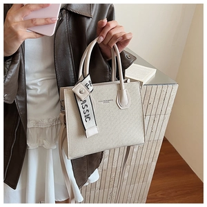 Détail d'un sac bandoulière minimaliste en cuir gaufré beige avec ruban tressé