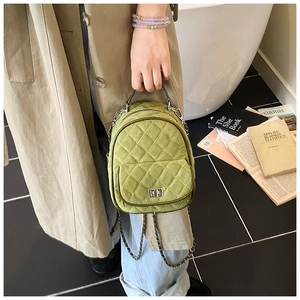Detailed side view of green quilted mini backpack with silver chain and twist lock clasp