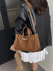 Brown hollow-out faux leather tote bag with laser-cut holes and adjustable shoulder strap