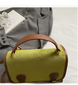 Detail of green suede backpack with brown leather handle and gold metal hardware