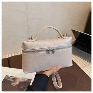 Close-up of beige crocodile pattern handbag with silver zippers in a stylish setting