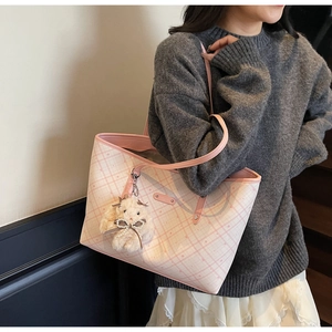 Dettaglio della borsa tote a quadri rosa con ciondolo a forma di orso sulla spalla