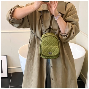 Close-up of green quilted mini backpack with chain straps and metallic twist lock detail