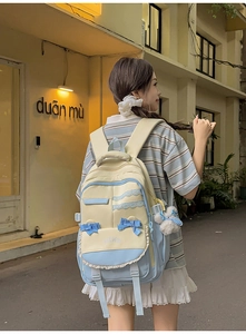Detail of preppy backpack side view with blue bow and plush charm on adjustable strap