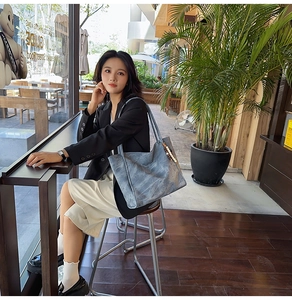 Gray-blue marble texture tote bag with shoulder straps shown in an outdoor street setting