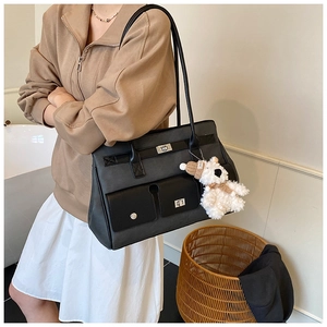 Detail of black matte leather tote bag featuring silver twist lock and plush charm
