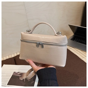 Detail of beige faux leather handbag with crocodile pattern texture and adjustable strap