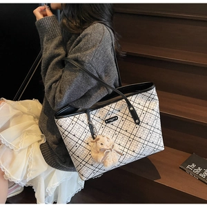 Dettaglio di una grande borsa tote a scacchi con ciondolo a forma di coniglio di peluche