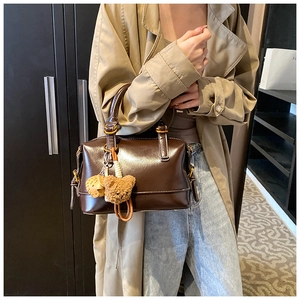 Detail of oil wax leather Boston bag with teddy bear charm and metallic D-ring attachment