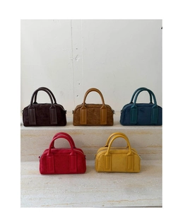 Collection of suede boston handbags in brown, yellow, teal and red on marble display