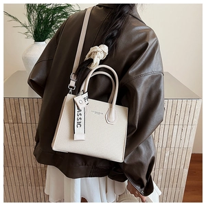 Détail du petit sac carré beige minimaliste avec logo et texture élégante