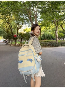 Outdoor shot of a sweet college style backpack in pastel yellow and blue with bow detail