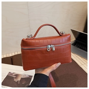 Close-up of orange-brown crocodile pattern leather bag with silver zipper and top handle