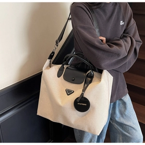 Detailed view of canvas tote bag with leather handles and removable shoulder strap