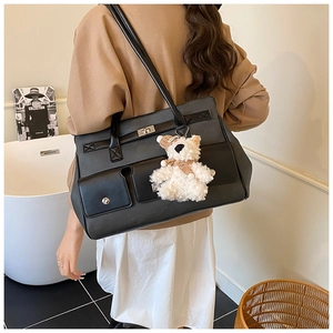Detail of a large black tote bag with silver hardware and a cute white bear charm