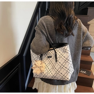 Dettaglio di una grande borsa tote casual con motivo a quadri e ciondolo a forma di orso