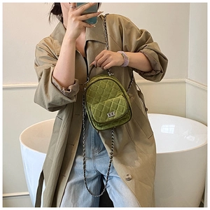 Detailed macro of green velvet mini backpack with quilted pattern and silver chain strap