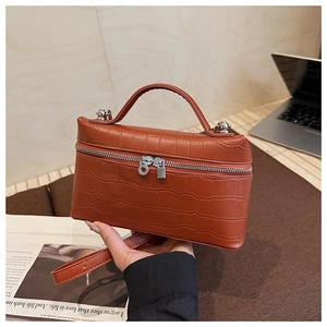 Close-up of crocodile pattern brick red handbag featuring dual zippers and silver hardware