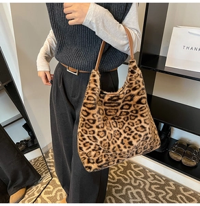 Faux fur leopard print tote bag with brown leather handles shown in a lifestyle setting