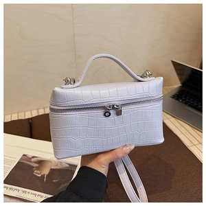 Close-up of light purple crocodile texture handbag with silver zippers and metal locks