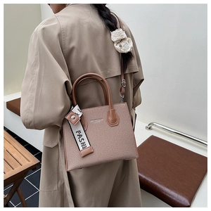 Détail du sac bandoulière en toile avec bordure en cuir marron et sangle tendance