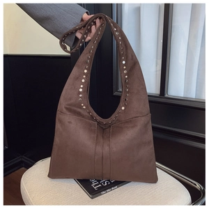 Gros plan d'un sac cabas en daim marron avec clous argentés et coutures verticales