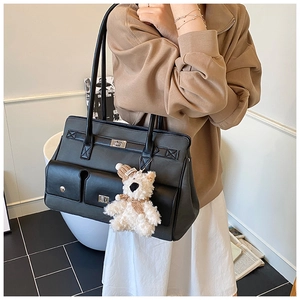 Detail of black PU leather tote bag with retro metal twist lock and cute bear charm