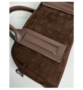 Detail of dark brown matte suede bowling bag with premium leather handles and stitching