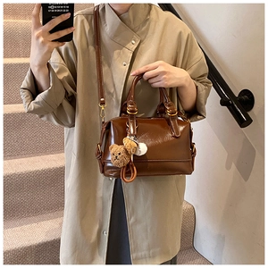 Detail view of brown vintage leather boston bag with cute bear and baseball charm
