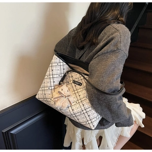 Dettaglio di grande borsa tote a quadri con ciondolo a forma di criceto e profili neri