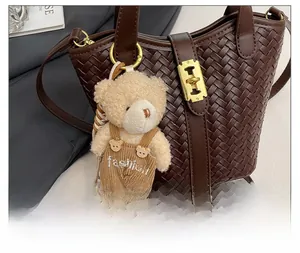 Dettaglio di un ciondolo a forma di orsetto su una borsa a secchiello intrecciata