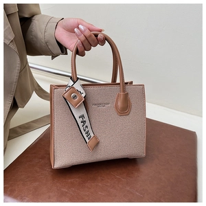 Détail d'un sac en toile kaki avec des poignées en cuir marron et un ruban chic