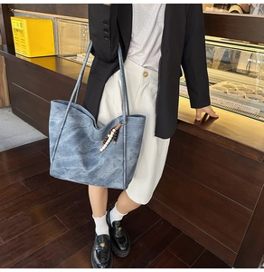Detail view of large grey-blue tote bag with wooden bead charm in a cafe setting
